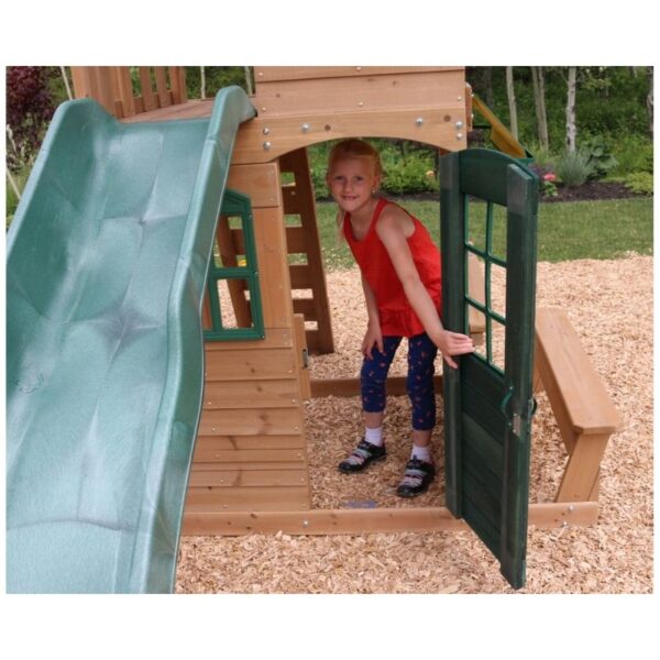 Kidkraft Windale Fort outdoor swing set featuring a wooden fort, swings, and a slide in a backyard setting.